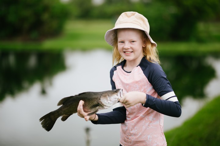 girl holding a barramundi fish