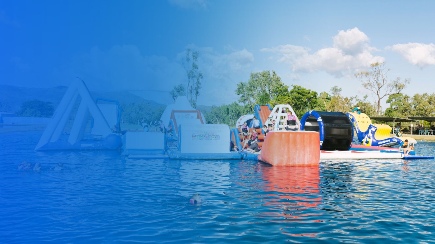 Inflatable aqua park obstacles on the lake with riders, Barra Fun Park